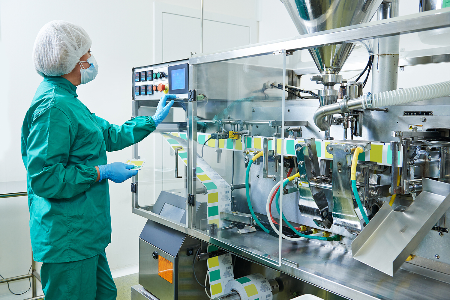 A worker at a pharmaceutical manufacturing plant enters commands into a control panel.